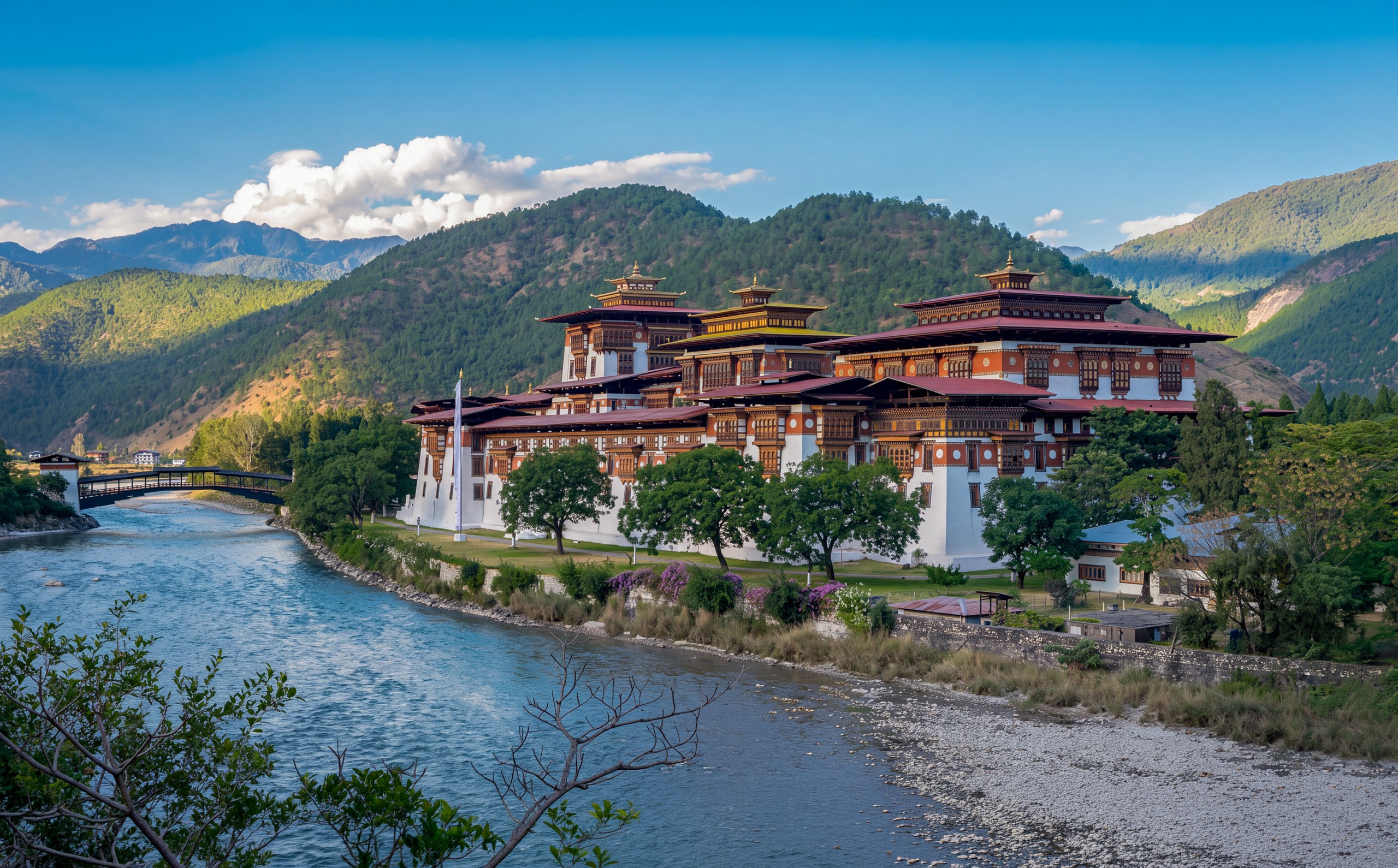 Punakha Dzong on the riverbank beneath forested hills