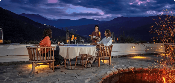 Guests dining by candlelight on a mountain terrace at dusk